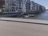 there is a man in white jacket walking along a bridge near water and buildings with boats