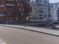 there is a man in white jacket walking along a bridge near water and buildings with boats