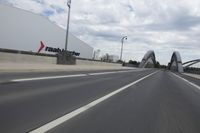 a large bridge over the road with trees in the background while traffic moves down it