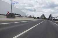 a large bridge over the road with trees in the background while traffic moves down it