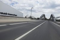 a large bridge over the road with trees in the background while traffic moves down it