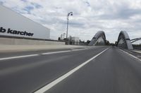 a large bridge over the road with trees in the background while traffic moves down it