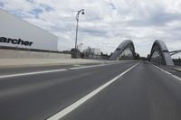 a large bridge over the road with trees in the background while traffic moves down it