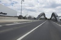 a large bridge over the road with trees in the background while traffic moves down it
