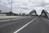 a large bridge over the road with trees in the background while traffic moves down it