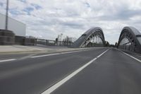 a large bridge over the road with trees in the background while traffic moves down it