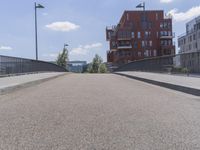 there is a bike going along an empty road near some buildings, and on a bridge