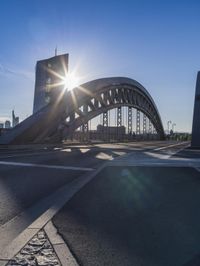 the sun shines brightly on a bridge over a highway in a city, as seen from the road level