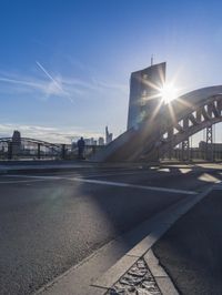 the sun shines brightly on a bridge over a highway in a city, as seen from the road level