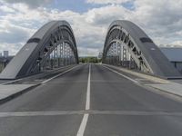 the road passes under a gray steel bridge that crosses it's length and ends to another one