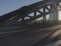 the man is on his motor bike on the highway by the bridge that connects to the city and a pedestrian