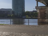 a man running down a street next to a river in front of some buildings that are high up