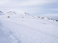 snow covered slope in the middle of a ski area as people ski on it near ski lift