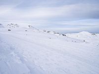 snow covered slope in the middle of a ski area as people ski on it near ski lift