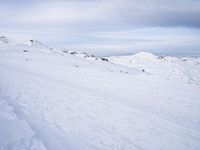 snow covered slope in the middle of a ski area as people ski on it near ski lift