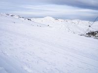 snow covered slope in the middle of a ski area as people ski on it near ski lift