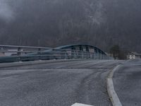 a long blue train traveling through a bridge next to trees and a mountain slope of mountains