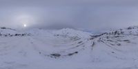 there are some snow covered mountains under a cloudy sky and skyway with tracks of skis