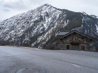 a house is in the middle of the road, and a mountain in the background