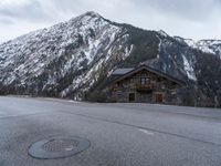 a house is in the middle of the road, and a mountain in the background