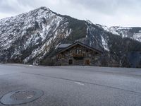 a house is in the middle of the road, and a mountain in the background