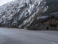 a house is in the middle of the road, and a mountain in the background