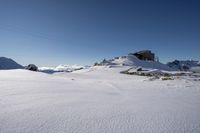 a mountain side covered in snow and rocks with a lodge on top of the mountain