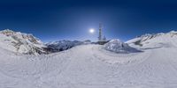 a panorama of a mountain top with snow on the ground and in the distance the sun is setting