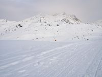 a skier is heading down the slope at a ski resort, near the mountains behind him