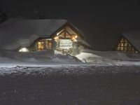 the night sky lights up the snowy lodge buildings and driveway area during a snowstorm