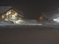 the night sky lights up the snowy lodge buildings and driveway area during a snowstorm