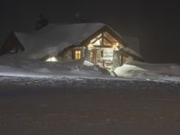 the night sky lights up the snowy lodge buildings and driveway area during a snowstorm