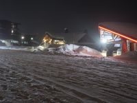 snowy mountain with ski slopes and buildings in the background at night light on dark night