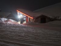 snowy mountain with ski slopes and buildings in the background at night light on dark night