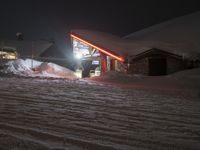 snowy mountain with ski slopes and buildings in the background at night light on dark night