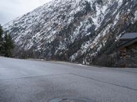 a parking meter sitting on the side of a road near a mountain with a slope behind it