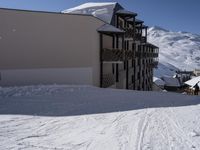 a ski lodge sits on top of the snowy mountain side with a few snow skiiers