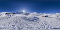 a ski slope and tracks in the snow on a clear day with a sun coming up