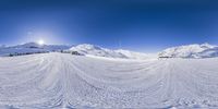 a large ski slope has snow on it, with hills and sky in the background