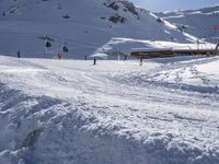 people skiing down the slopes near the snow covered ski slopes with mountains in the background