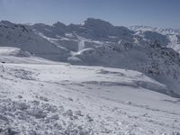 a person skiing on a snow covered mountain slope with mountains in the distance at high altitude