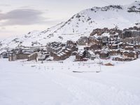 a person is standing on the ski slope near the snow covered mountain village that's surrounded by a line of cable cars