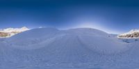 a snow covered mountain with a ski slope in front of it and a blue sky