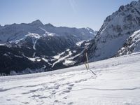 a man in a red jacket is standing on the mountain slope with two snow skis and poles