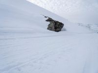 there is a person skiing on snow covered slope in the wintertime with clouds above