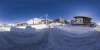 snow and ski slope with a big house in the background, taken using fish eye lens