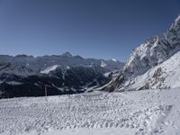 a person riding skis down a snow covered slope under a blue sky with mountains in the background