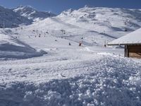 a small ski lodge is on the mountains covered in snow as skiers and snowboarders descend up