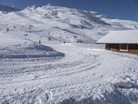 a small ski lodge is on the mountains covered in snow as skiers and snowboarders descend up