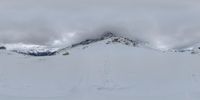 a person standing in the snow with skis on in front of them, looking down from a hill